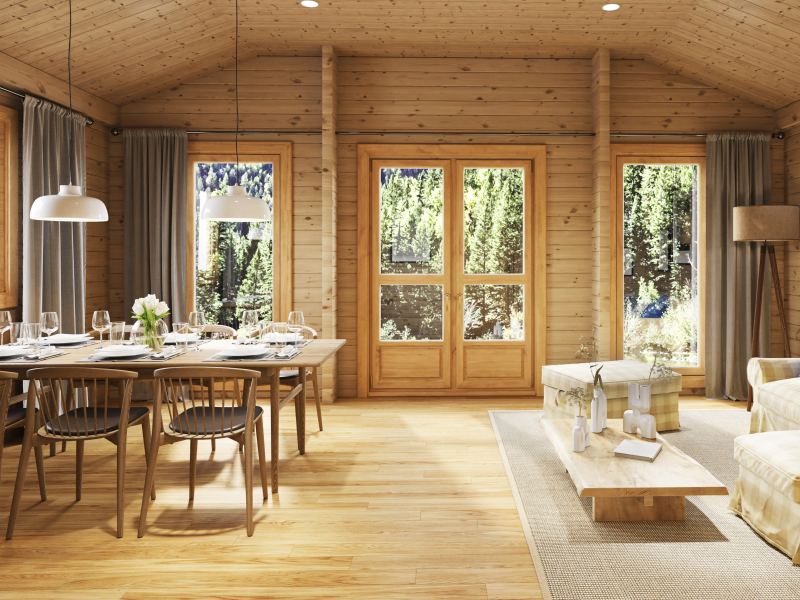 Ein geräumiges Esszimmer aus Holz mit gedecktem Tisch, großen Fenstern und bequemen Sitzgelegenheiten, beleuchtet durch Tageslicht.