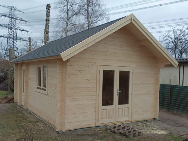 Neu gebaute kleine Holzhütte mit Satteldach und einer Vordertür mit Glasscheiben.