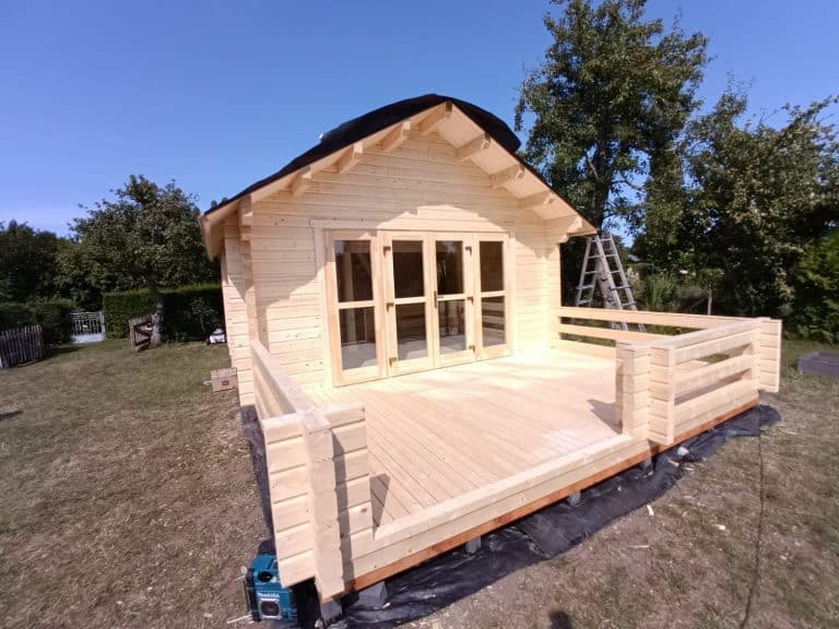 Auf einem Hof wird eine Holzhütte gebaut.