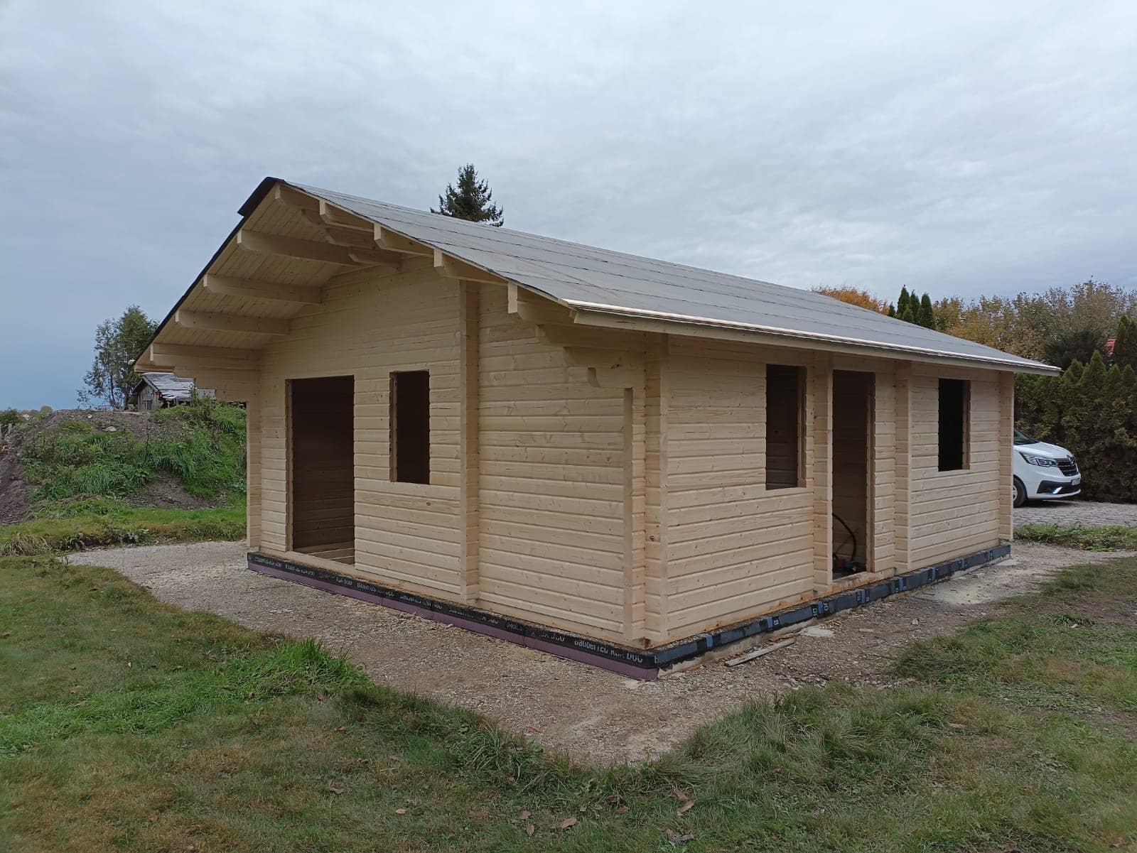 Auf einem Feld wird eine kleine Blockhütte gebaut.